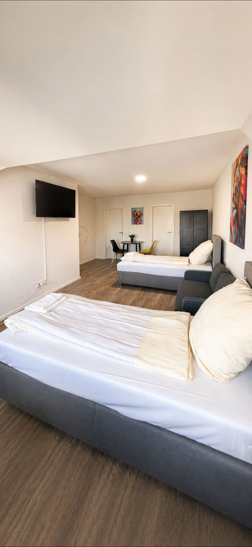 Zimmer mit mehreren Einzelbetten, Sofa und Fernseher