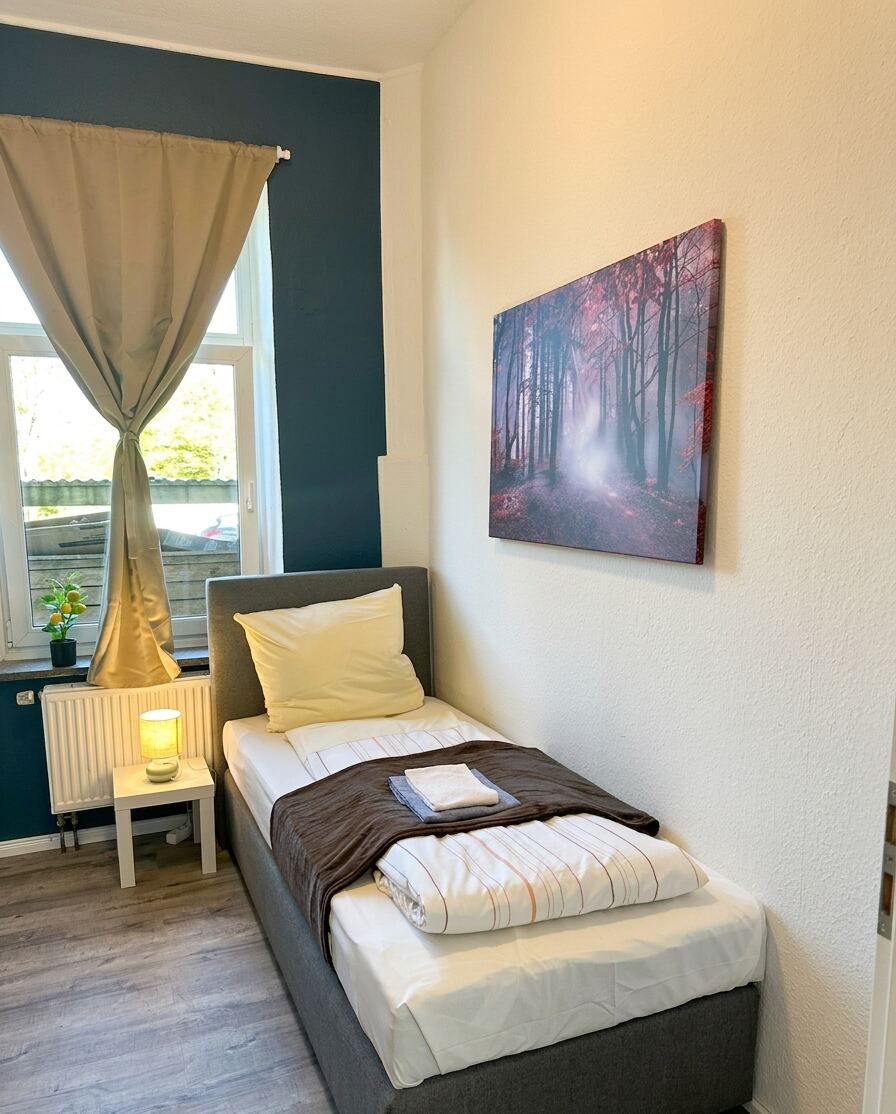 Helles Einzelzimmer mit Fenster und Wandbild